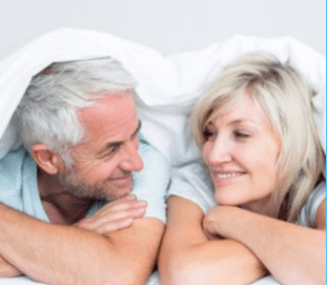 Intimate moment of a couple in bed, wrapped in each other's arms.